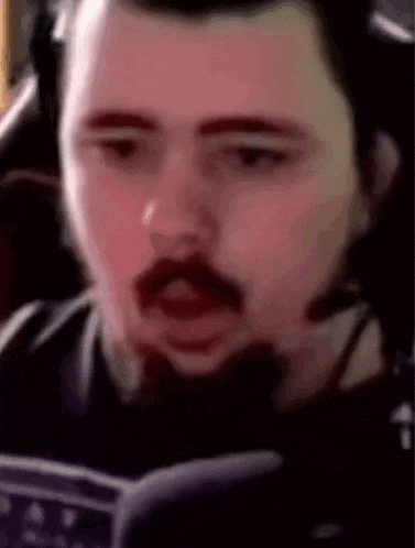 a man with a mustache is wearing headphones and a headset while playing a video game .