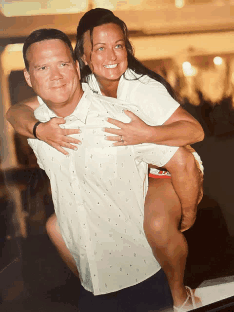 a man is carrying a woman on his back and she is smiling