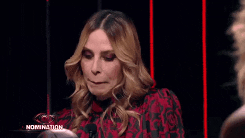a woman in a red and black dress is making a funny face while sitting in front of a microphone .
