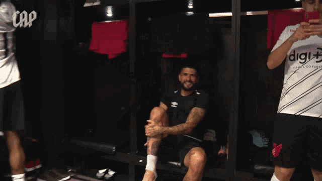 a man sits in a locker room wearing a shirt that says digi +