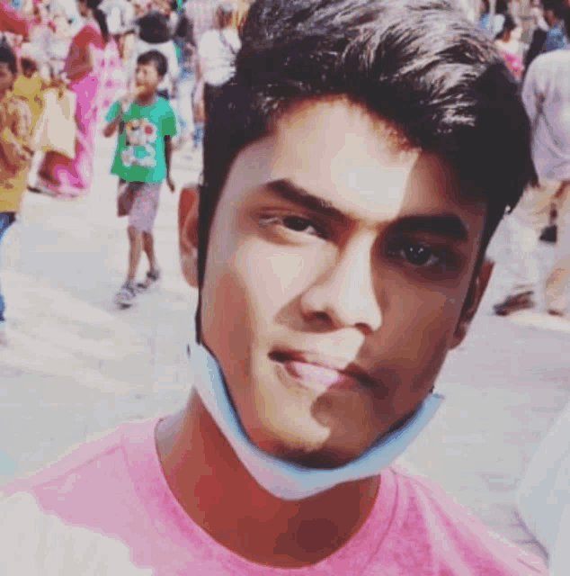 a young man wearing a pink shirt and a mask on his face