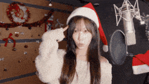 a woman is wearing a santa hat and pointing to her head