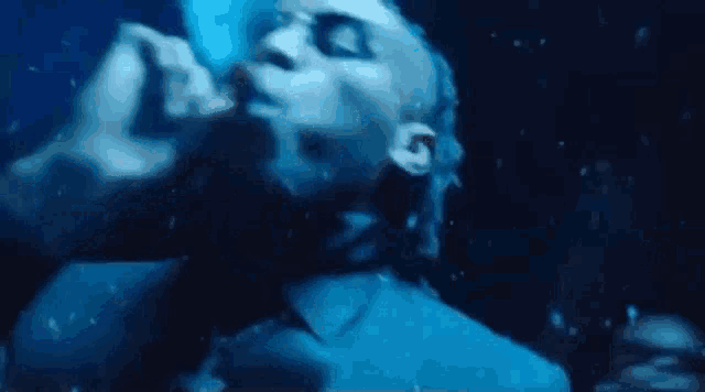 a man is swimming underwater in a dark room with a microphone in his hand .