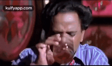 a man is drinking a glass of wine while sitting in a restaurant .