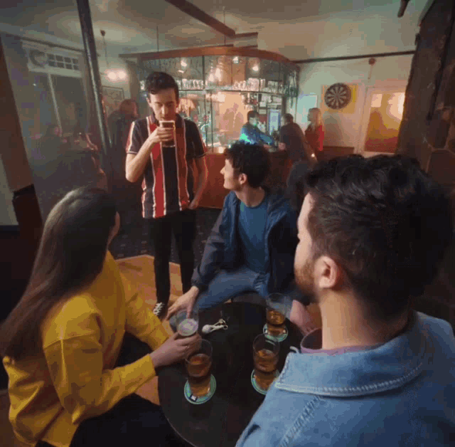a group of people sitting around a table with a dart board in the background