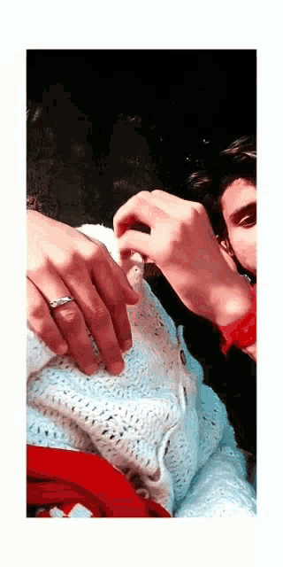a man and a woman are holding hands and the woman is wearing a ring on her finger .