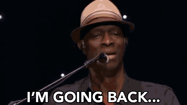 a man in a hat is singing into a microphone .