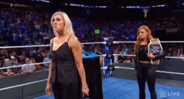 two women are standing in a wrestling ring and one is holding a wwe belt
