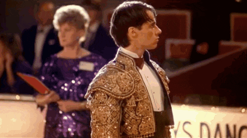 a man in a suit and bow tie is standing in front of a crowd .
