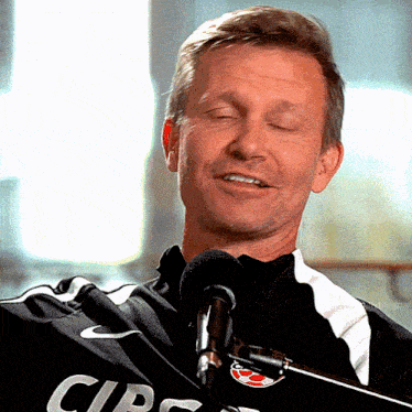 a man is singing into a microphone wearing a shirt that says cir