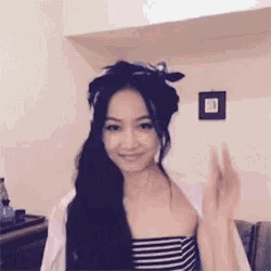 a woman wearing a striped top and a scarf on her head waves her hand