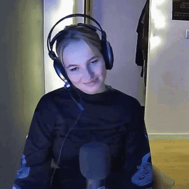 a woman wearing headphones and a microphone looks at the camera