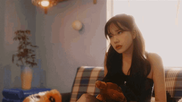 a woman sits on a couch holding a stuffed animal