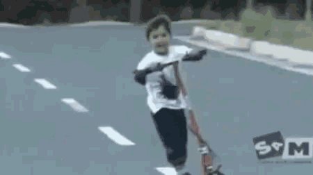 a young boy is riding a scooter on a street with a s & m logo in the background .