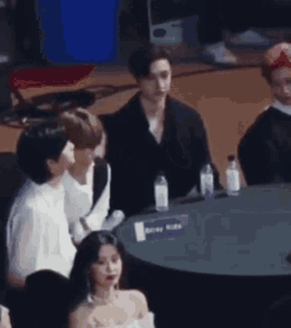 a group of people are sitting at a table with bottles of water .