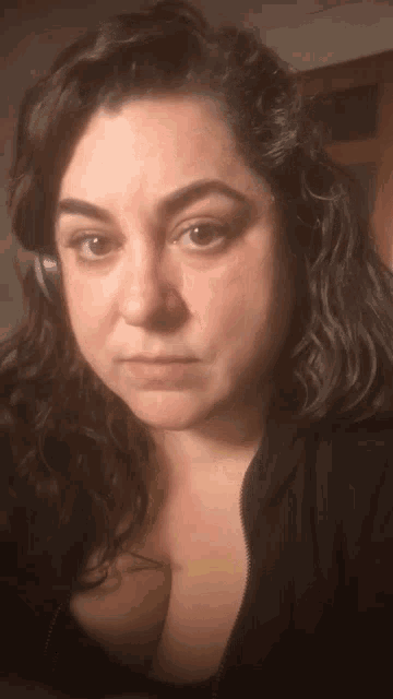 a woman wearing headphones and a black shirt looks at the camera