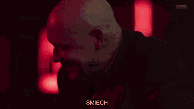 a bald man in a dark room with a caption that says nic nie trzeba nigdy nic nie trzeba młody czlowieku