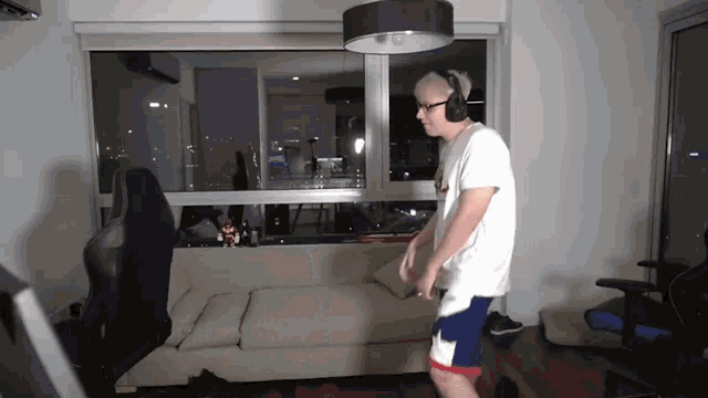 a man wearing headphones stands in front of a couch in a living room