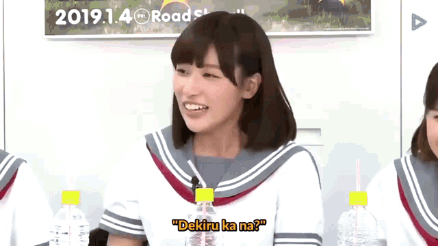 a girl in a school uniform is smiling and holding a bottle of water