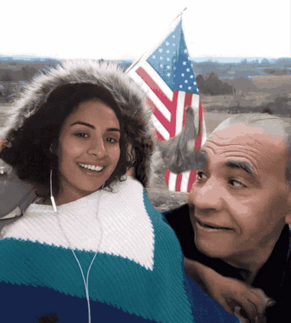 a man and a woman posing for a picture with an american flag in the background