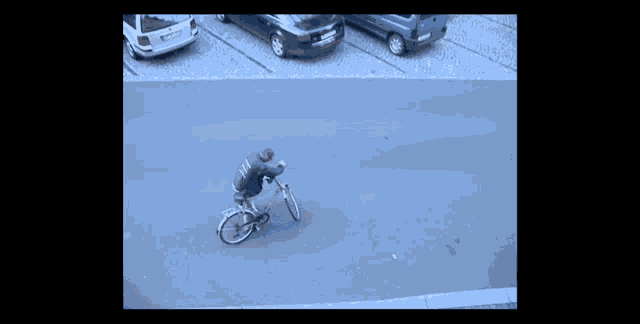 a man is riding a bike down a street with cars parked in the background