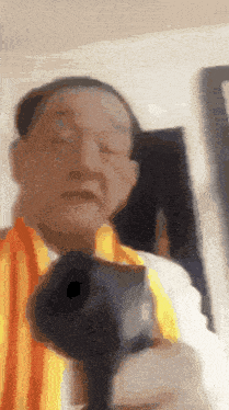 a man in a yellow and orange striped shirt is holding a camera .