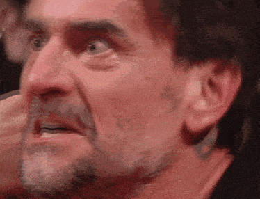 a man with a beard is looking at the camera with a surprised look on his face