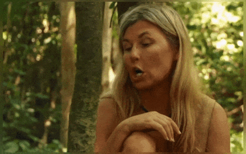 a woman is sitting in the woods with her mouth wide open