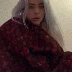 a woman with long white hair is covered in a red blanket .