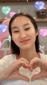 a woman is making a heart with her hands .