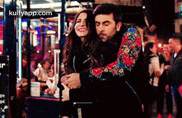 a man and a woman are hugging each other in a crowded city street .