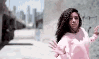 a woman with curly hair is wearing a pink shirt