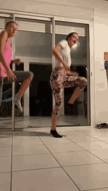 two women are jumping in the air in front of a door