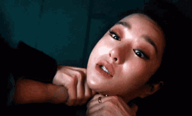a close up of a woman 's face with a hand on her neck