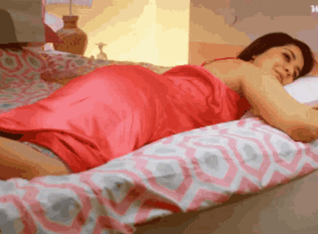 a woman in a red dress is laying down on a bed