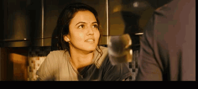 a woman with a bindi on her forehead talks to a man in a kitchen