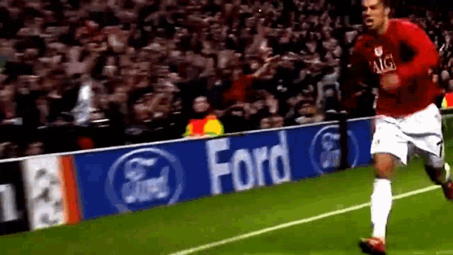a soccer player is running on the field in front of a ford sign