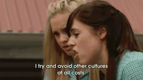 two girls are sitting next to each other and one of them is saying i try and avoid other cultures at all costs