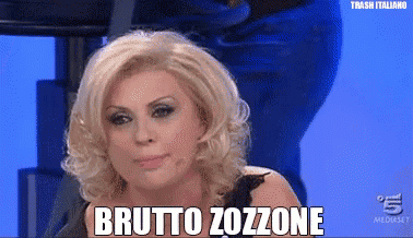 a woman with blonde hair is sitting in front of a blue background and says brutto zozzone