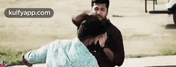 two men are fighting each other on a sidewalk in a park .