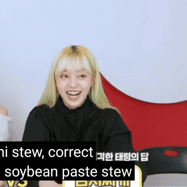 a woman in a black shirt is smiling in front of a sign that says soybean paste stew