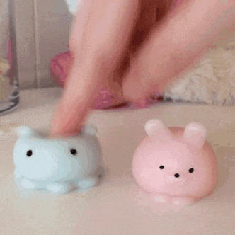 a person is playing with a blue bear and a pink rabbit .