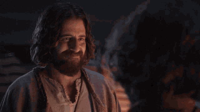 a man with a beard and long hair looks at another man