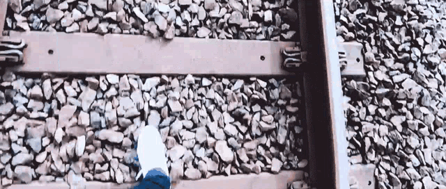 a person is walking on a train track with their foot on the tracks .