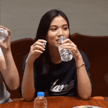 a woman wearing a shirt that says yankees drinks water from a bottle