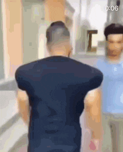 a man in a black shirt is standing next to another man in a blue shirt in a room .