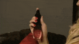 a blonde woman is sitting on a couch with a red pillow and holding a ring .