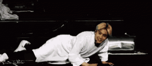 a man in a white robe is laying on the floor with his legs crossed .