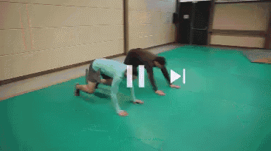 a person is crawling on a green mat with a white arrow pointing to the left