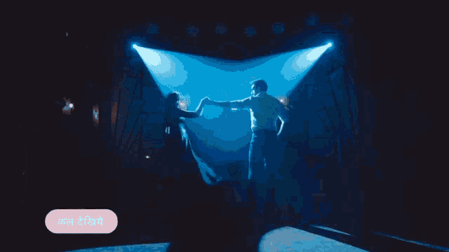 a man and woman are dancing in a dark room with a pink button that says ' कल देखो ' on it